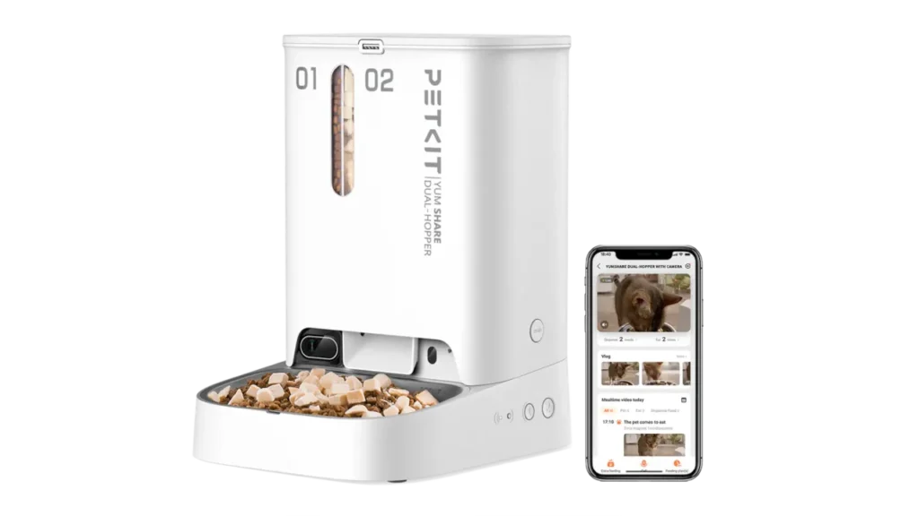 White PETKIT YumShare Dual Hopper smart feeder next to a smartphone showing the live camera feed.