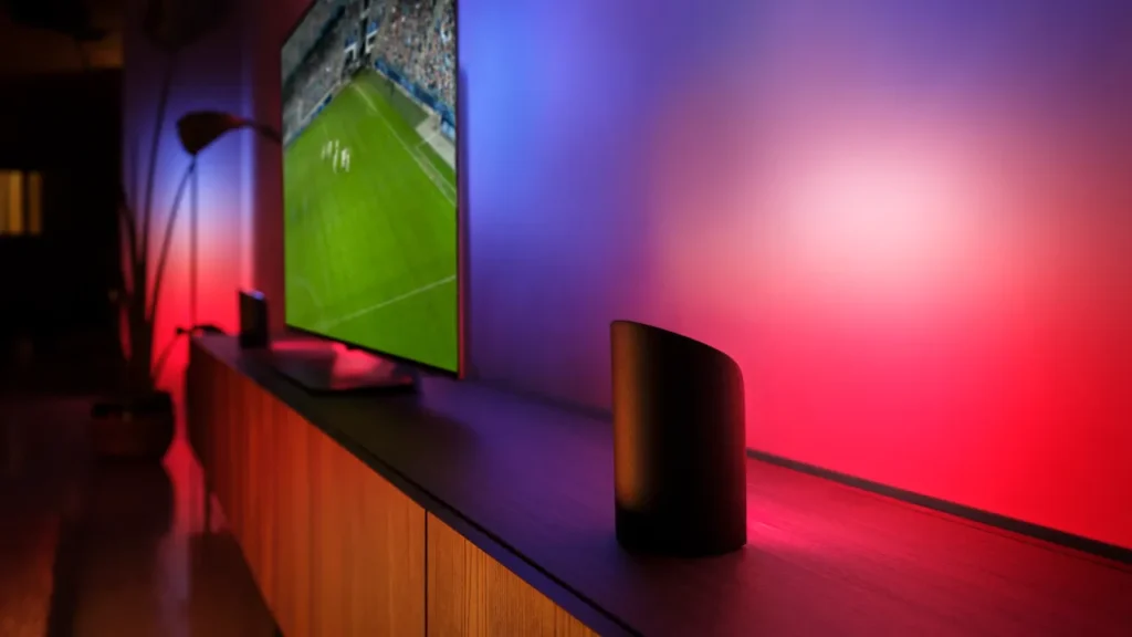 A Philips Hue Play lightbar casting colorful ambient light behind a television screen.