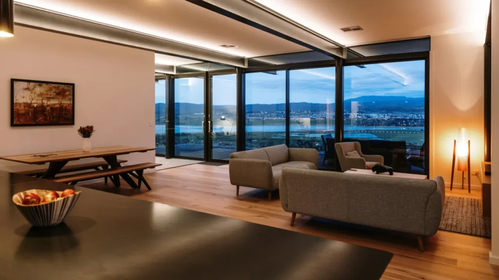 A modern, open-plan living and dining area with warm white ambient smart lighting in the ceiling coves.