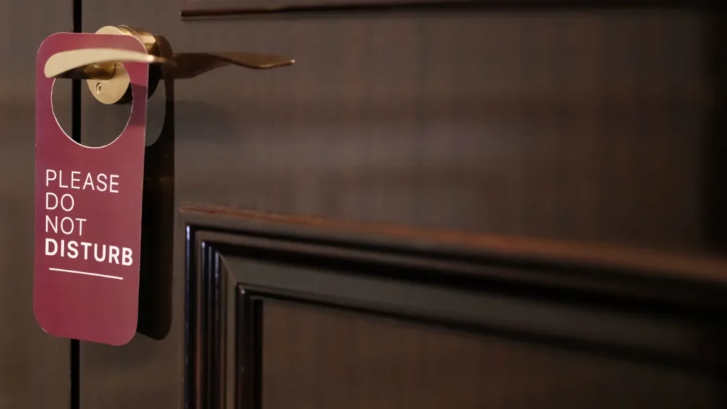 Do Not Disturb door hanger on a wood-paneled door handle.