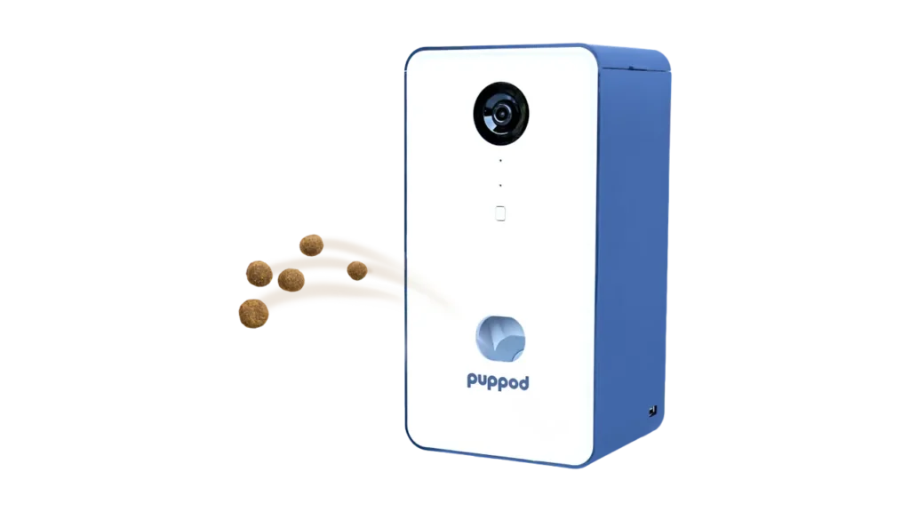 The white and blue PupPod smart treat dispenser actively shooting out pieces of dog kibble.